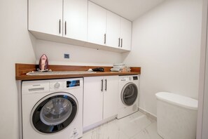 Een wasserette met twee wasmachines, een droger en een houten aanrecht met diverse spullen.