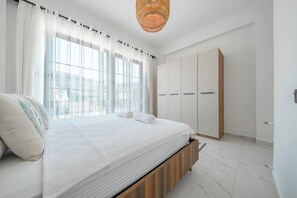 Een slaapkamer met een bed, een kledingkast en een raam met gordijnen.