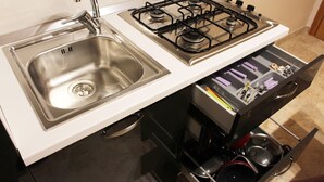 A kitchen with a stainless steel sink, a gas stove, and a drawer organizer with utensils.