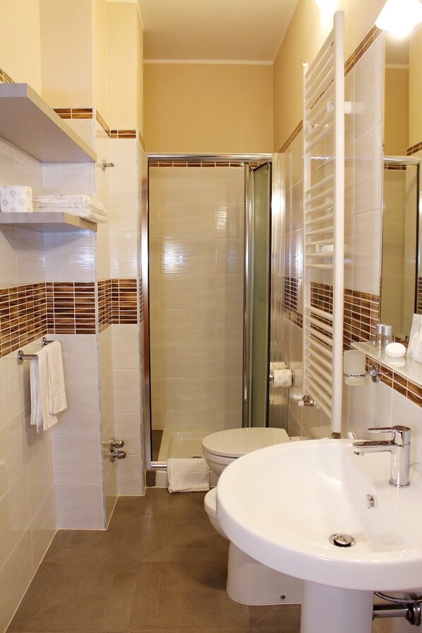 Een badkamer met douche, toilet en wastafel.