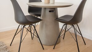 Un comedor moderno con una mesa redonda y cuatro sillas negras.