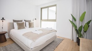 Un dormitorio moderno con una cama grande, una mesita de noche, una lámpara de pie, un ventanal y una planta en maceta.
