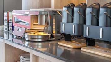 Een buffetopstelling met een bedieningsstation voor eten, inclusief een rasp, een warmhoudapparaat en diverse bestek.