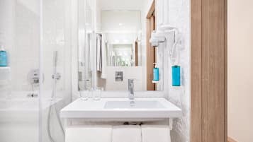 A modern bathroom with a glass shower enclosure, a white sink, and a mirror.