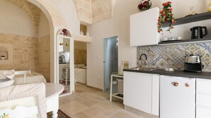 A compact kitchen with white cabinets, a black coffee maker, and a tiled backsplash.