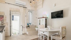 A spacious room with a white dining table, chairs, and a TV mounted on the wall.