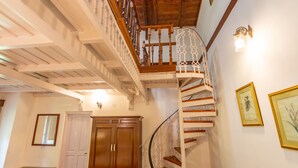 Una escalera de caracol con barandillas de madera y una pared blanca con cuadros enmarcados.