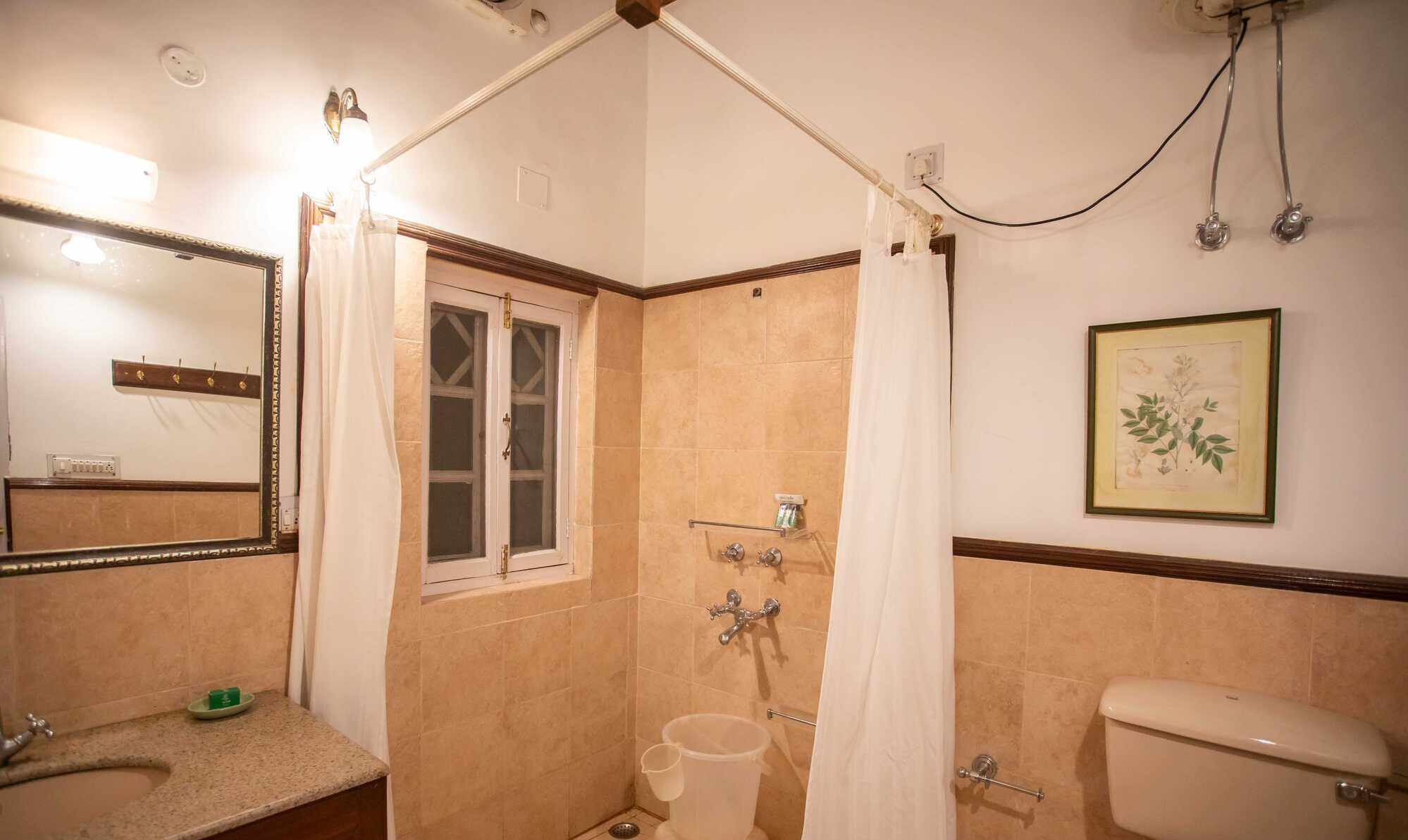 Un baño con ducha, inodoro, lavamanos e ilustración botánica enmarcada en la pared.