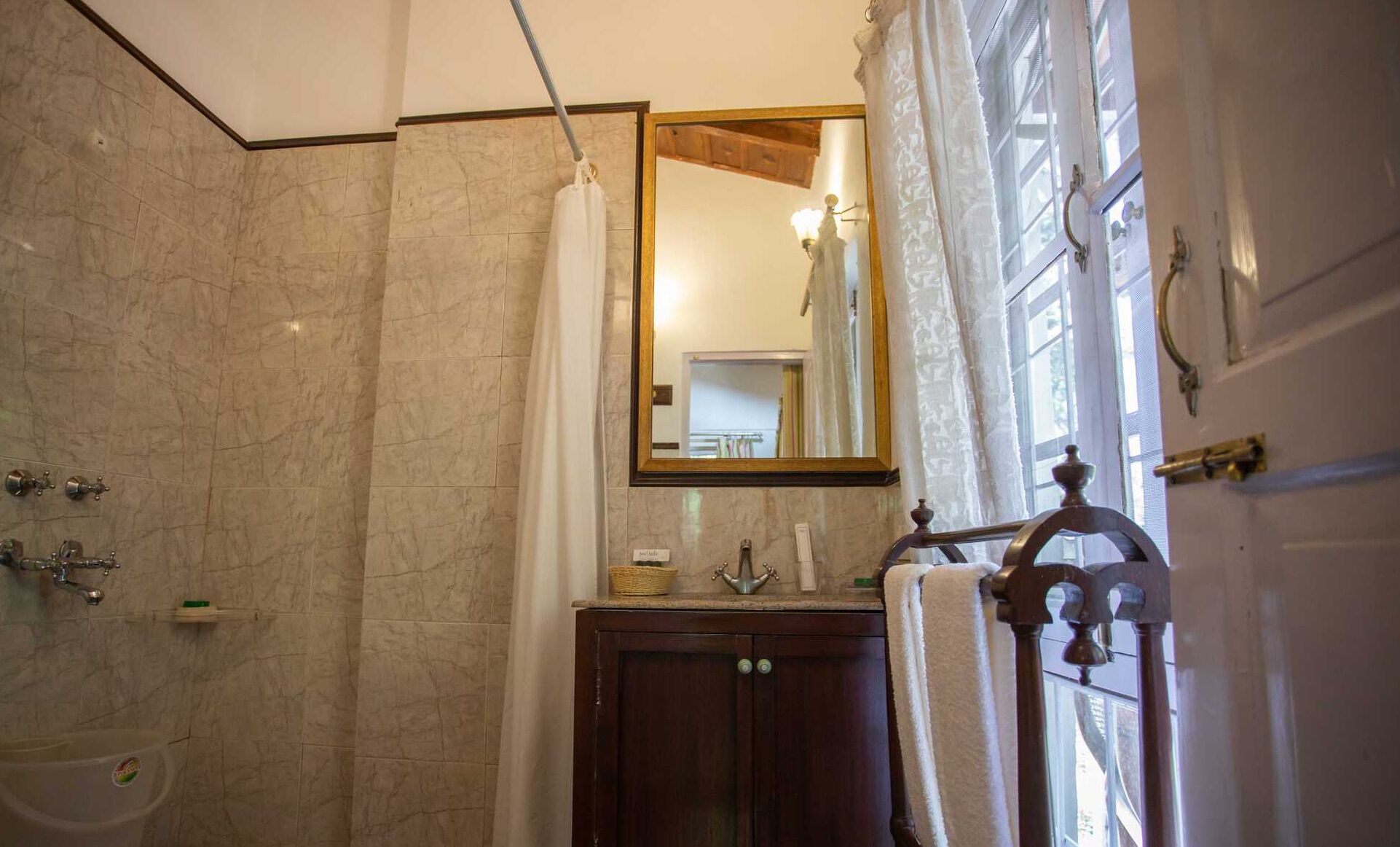 Un baño con pared de mármol, un armario de madera, un espejo y una bañera.