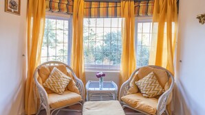 Una habitación acogedora con dos sillones de mimbre, una mesita y un banco.