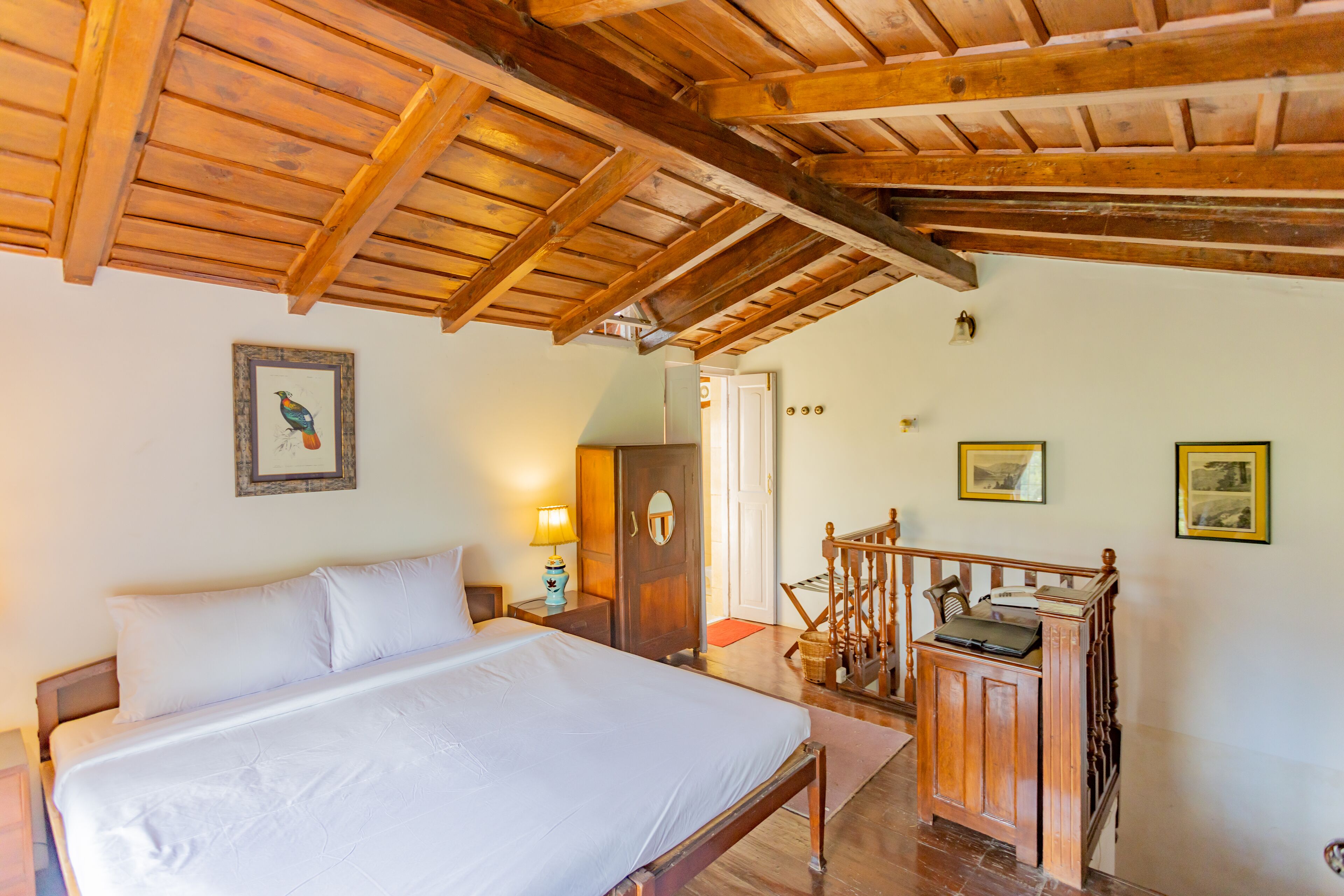 Een slaapkamer met een houten bed, een houten dressoir en een trap met een houten leuning.