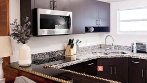 A modern kitchen with dark cabinets, a stainless steel microwave, granite countertop, and a visible rope on the island.