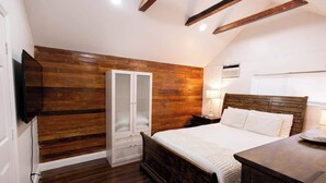 A bedroom with a wooden wall panel, a bed with white bedding, a bedside table, and a wardrobe with frosted glass doors.