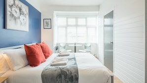 A neatly arranged bedroom with a bed, pillows, and a window with blinds. - The Modern Cambridge Studio 4 (Cambridge)