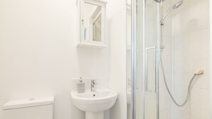 A modern bathroom with a glass-enclosed shower, a white sink, and a toilet. - The Modern Cambridge Studio 4 (Cambridge)