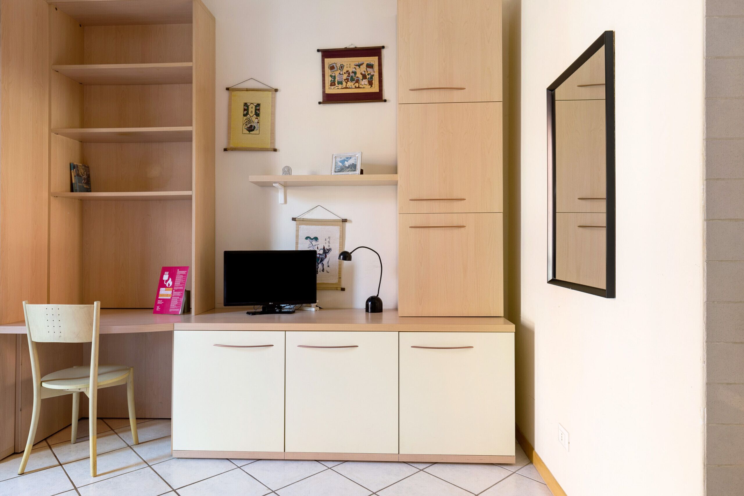 Een werkplek met een bureau, stoel, planken en een televisie.