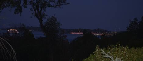 A nighttime view of a coastal cityscape with a prominent bridge and distant city lights.