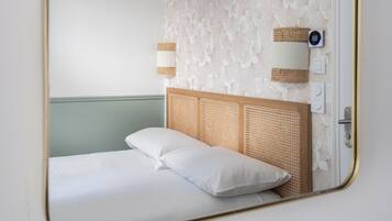 Une chambre à coucher avec un lit, une lampe fixée au mur et une prise de courant.