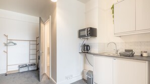 A compact kitchen with white cabinets, a microwave, a kettle, and a sink. - The Modern Cambridge Studio 5 (Cambridge)