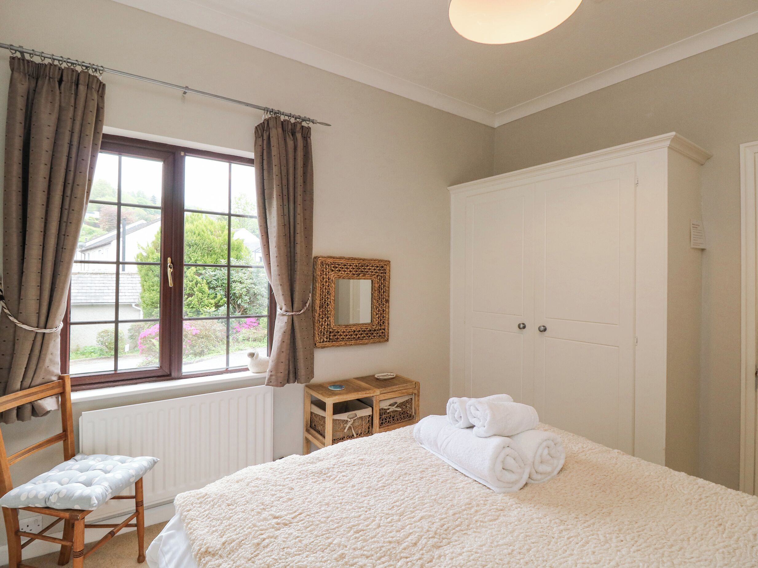 A bedroom with a large bed, a wooden chair, a dresser, and a wardrobe.