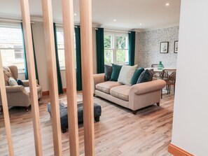 A living room with a beige sofa, a coffee table, and a dining area with a table and chairs. - 2 Apple Tree (Chathill)