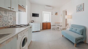 A compact living space with a kitchen, a dining area, and a sofa. - Stella Maris by Wonderful Italy (Cefalù)