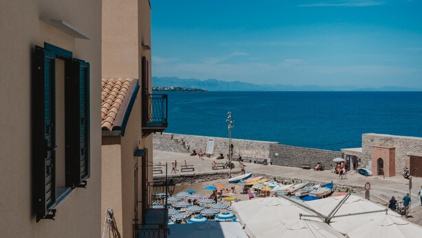 A coastal town with a stone wall, beach umbrellas, and a clear view of the sea. - Stella Maris by Wonderful Italy (Cefalù)