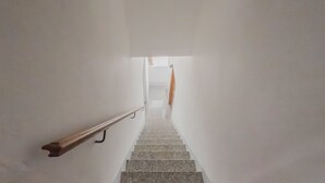 A staircase with a handrail, leading to a bright room with a window and a curtain. - Stella Maris by Wonderful Italy (Cefalù)