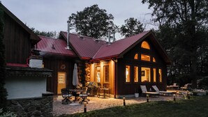 A log cabin with a stone patio, outdoor seating, and a fireplace. - Timber Sky Estate - Family & Pet-Friendly Log Cabin in Elora (West Montrose)