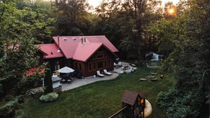 A large wooden cabin with a red roof, surrounded by a well-maintained lawn and trees. - Timber Sky Estate - Family & Pet-Friendly Log Cabin in Elora (West Montrose)