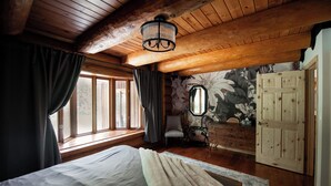A cozy bedroom with a large bed, wooden ceiling, and a window with curtains. - Timber Sky Estate - Family & Pet-Friendly Log Cabin in Elora (West Montrose)