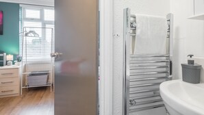 A modern bathroom with a white sink, chrome towel rack, and a glass shower enclosure. - The Modern Cambridge Studio 6 (Cambridge)