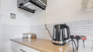 A kitchen with a wooden countertop, a kettle, and a white tiled backsplash. - The Modern Cambridge Studio 6 (Cambridge)