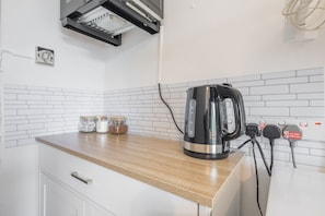 Enjoy cooking in this well-equipped kitchen with a stainless steel range hood, electric kettle, and ample cabinetry.