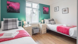 A modern bedroom with two beds, teal walls, and artwork. - The Modern Cambridge Studio 6 (Cambridge)