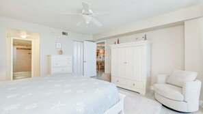 Ein Schlafzimmer mit Bett, Kommode, Kleiderschrank, Stuhl und Deckenventilator.