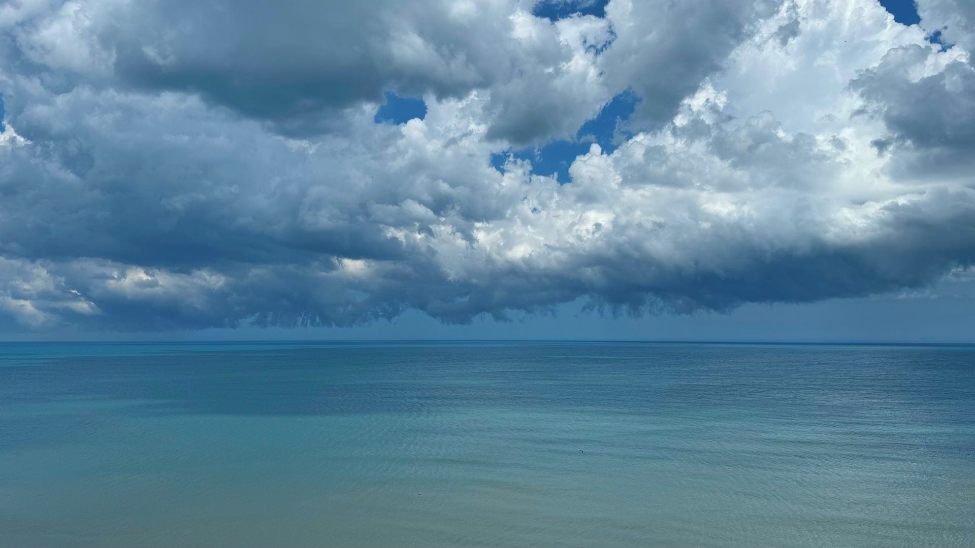 A clear view of the ocean under a cloudy sky.
