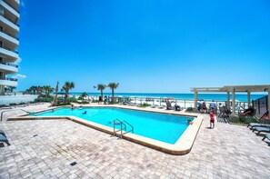 A swimming pool with a view of the beach, lounge chairs, and a covered area. - Panoramic Ocean and River Views! Seychelles Condominium Unit 1402 (Daytona Beach Shores)