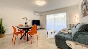 A modern living room with a dining area, a sofa, and a TV. - (003)  Helena Garden City Trip (Antibes)