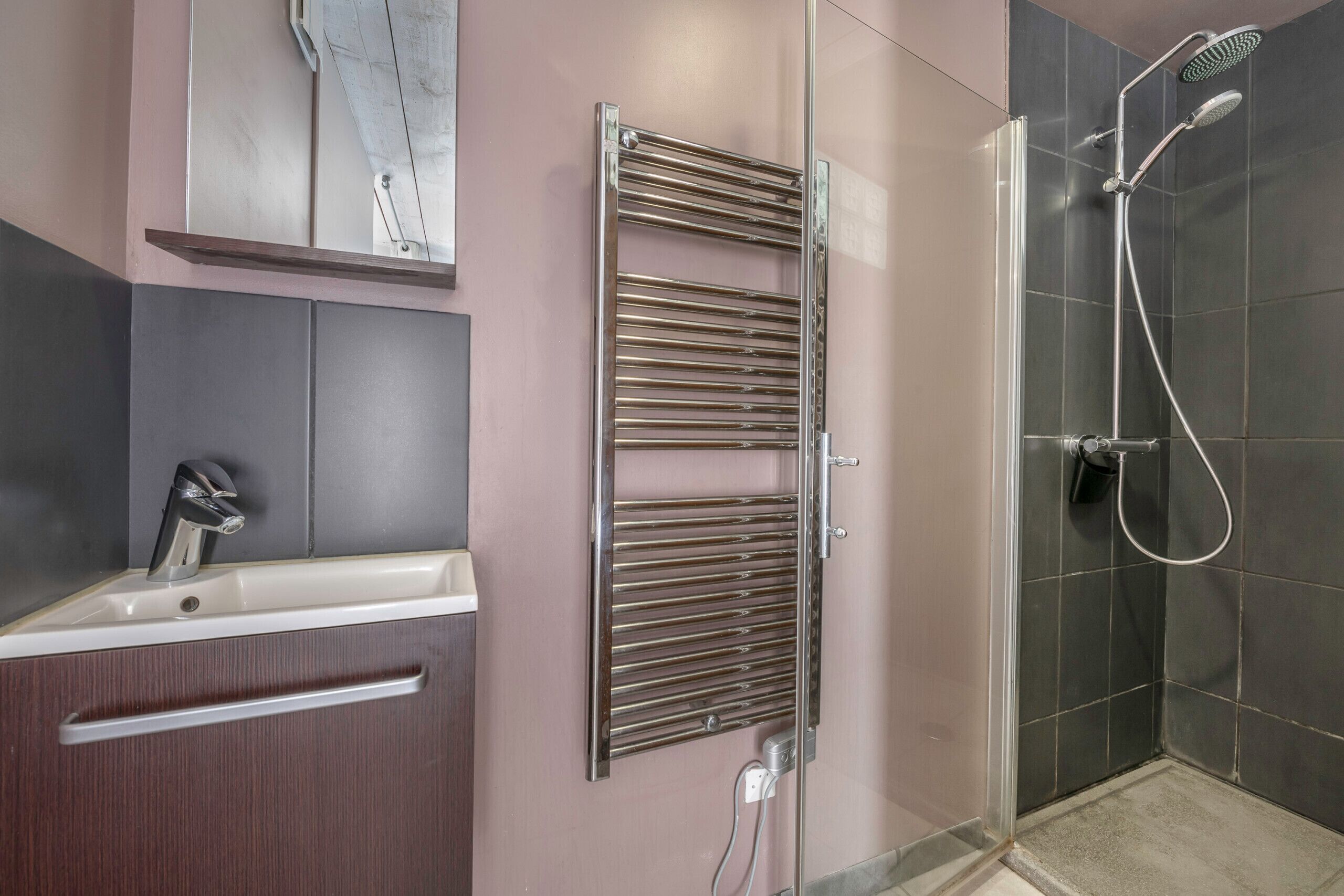 A modern bathroom with a built-in shower, a vanity with a mirror, and a towel rack.