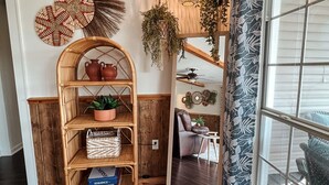 A cozy room with a wooden bench, shelves with decorative items, a hanging light fixture, and a view through a window with patterned curtains. - Woodland Bungalow-Hot Tub, Boat Dock, + Game Room (Royal)