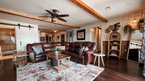 A spacious living room with a leather sectional sofa, a wooden coffee table, and a patterned rug. - Woodland Bungalow-Hot Tub, Boat Dock, + Game Room (Royal)