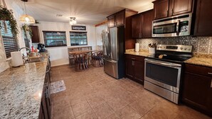 A modern kitchen with dark wood cabinets, stainless steel appliances, and a granite countertop. - Woodland Bungalow-Hot Tub, Boat Dock, + Game Room (Royal)