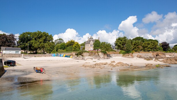 A beach with clear water, a large building in the background, and a few people near the water. - Cozy stay for 2, terrace, 400m from beach (Fouesnant)
