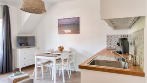 A modern kitchen with a wooden countertop, white cabinetry, and a built-in sink. - Cozy stay for 2, terrace, 400m from beach (Fouesnant)