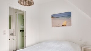 A bedroom with a bed, a picture of a beach, a shower, and a bedside table. - Cozy stay for 2, terrace, 400m from beach (Fouesnant)