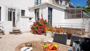 A dining table with a bowl of fruit, a pitcher, and a plate with cutlery. - Cozy stay for 2, terrace, 400m from beach (Fouesnant)