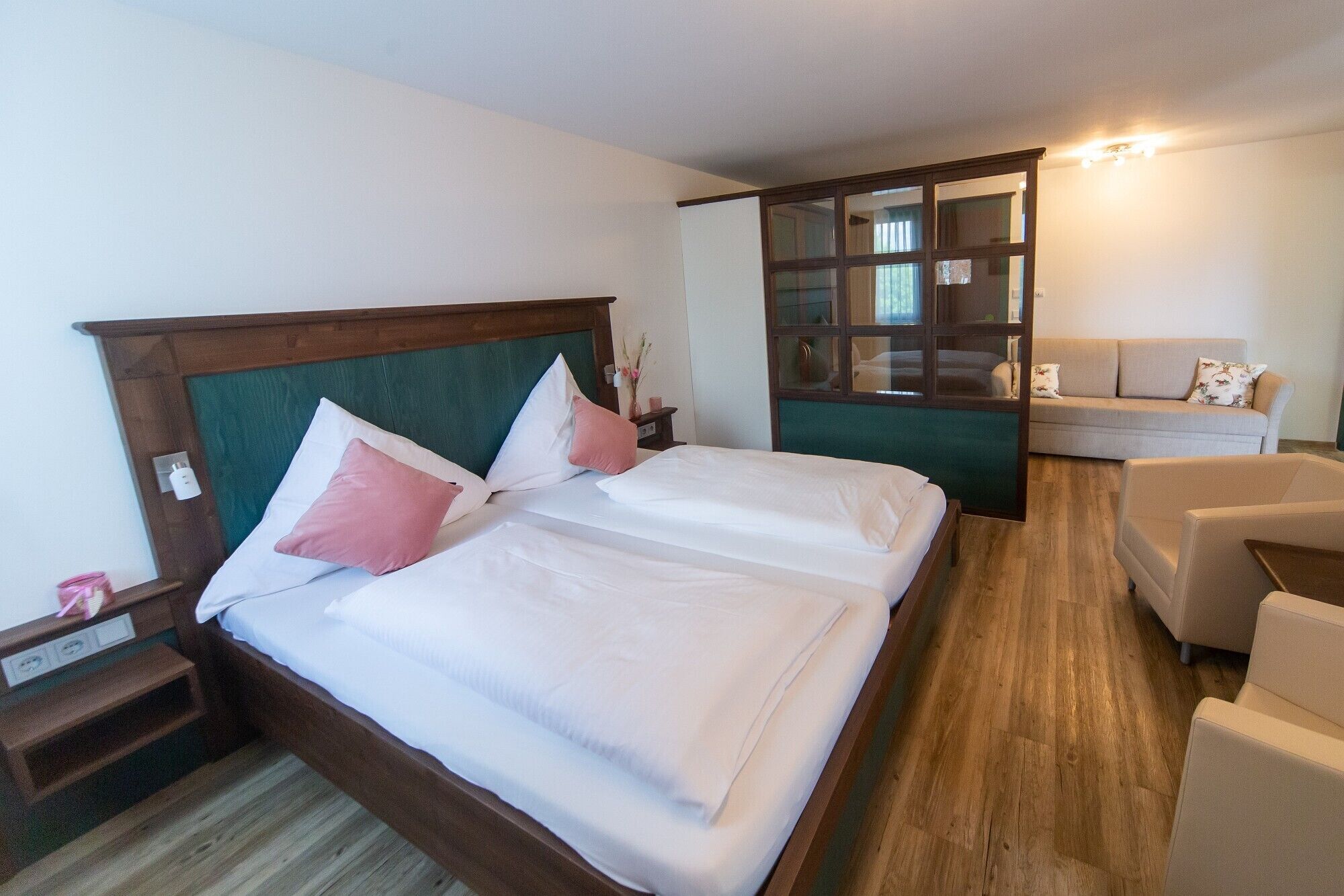 Een keurig ingerichte hotelkamer met een groot bed, een zithoek met een bank en een kleine tafel.