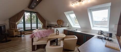A modern loft-style living space with a kitchen area, a dining area with a round table, and a cozy seating arrangement.