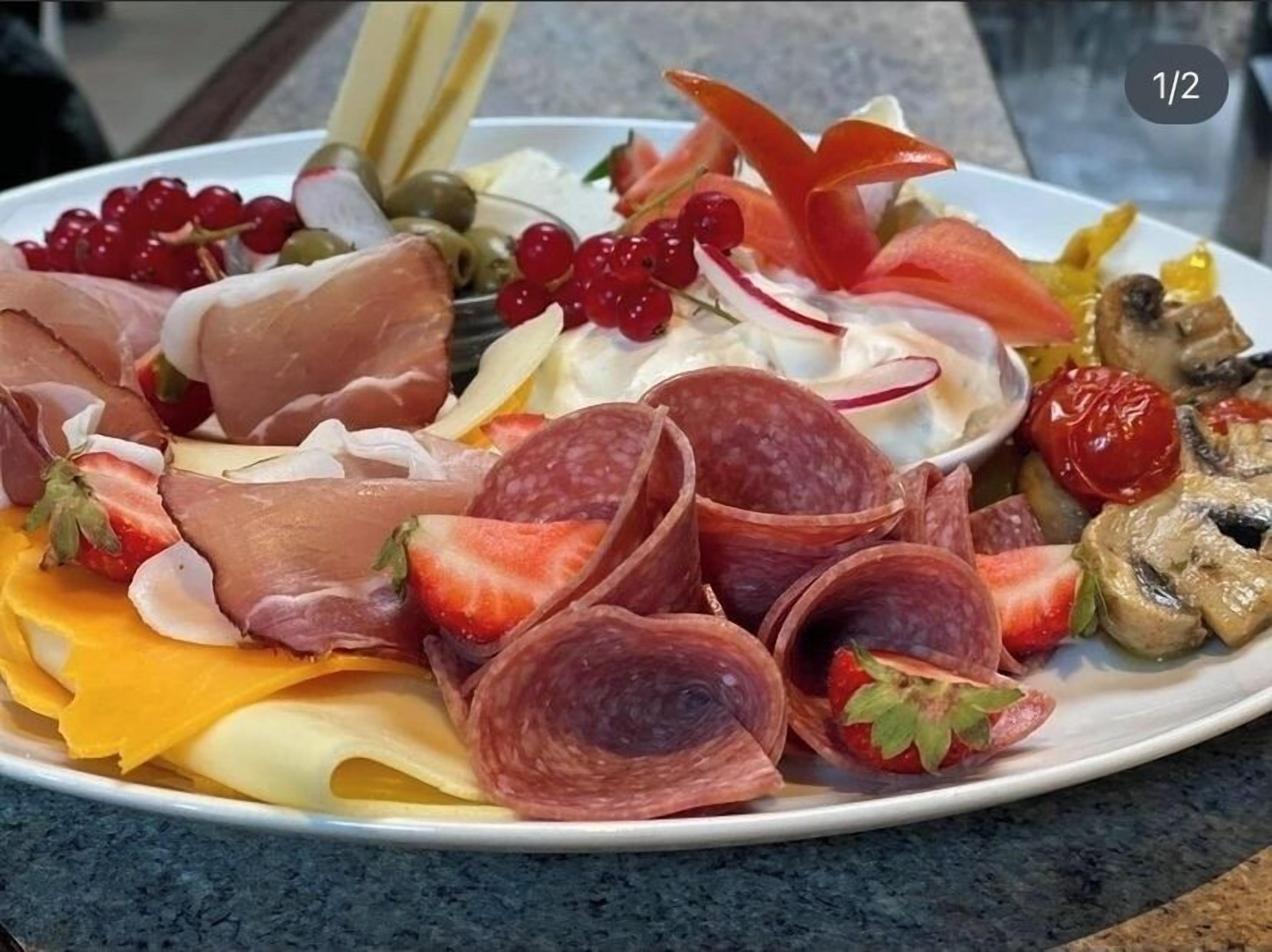 Eine Platte mit verschiedenen Wurstwaren, Käsesorten und Früchten.